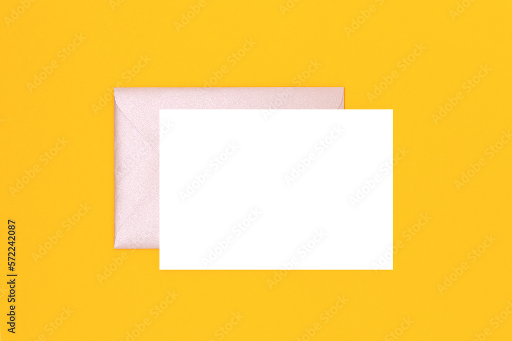 Clean white paper mockup and silver glittering envelope on a yellow background. Creative concept.