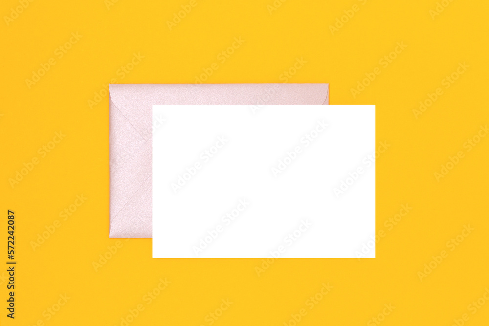 Clean white paper mockup and silver glittering envelope on a yellow background. Creative concept. Clean white paper mockup and silver glittering envelope on a yellow background. Creative concept.