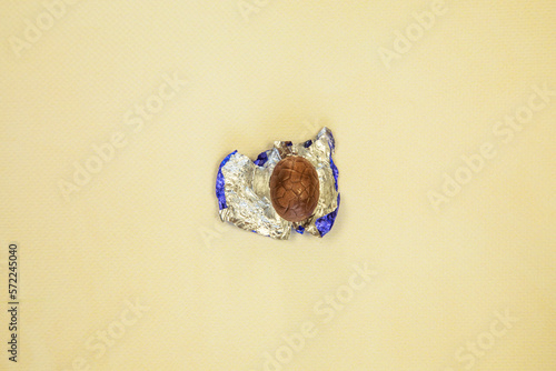 фотографія Chocolate Easter eggs wrapped in shiny blue foil yellow background, flat lay top