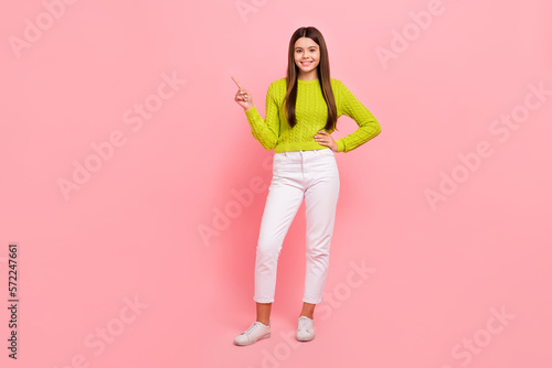 Full size photo of pretty young schoolgirl point empty space suggest look wear trendy green garment isolated on pink color background