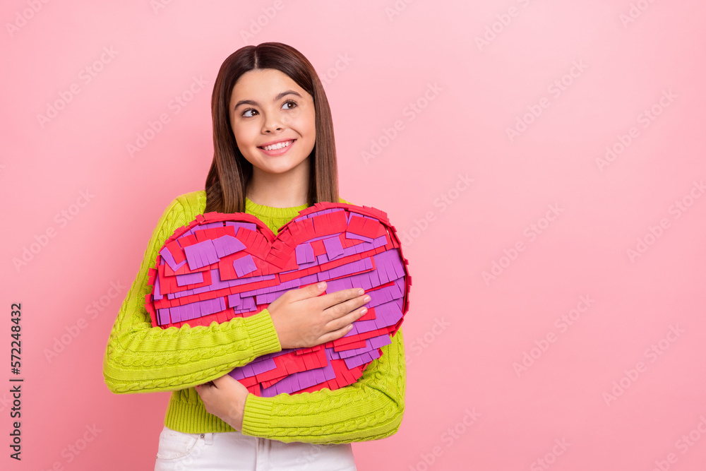 Photo of cheerful schoolgirl arms hold big heart collage look empty space isolated on pink color background Photo of cheerful schoolgirl arms hold big heart collage look empty space isolated on pink color background