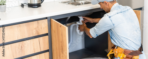 Tableau sur toile plumber fixes sink siphon by two pipe-wrenches in kitchen.