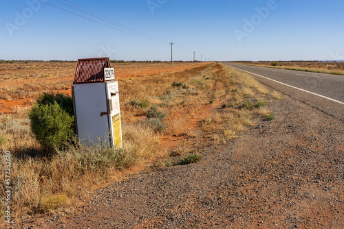 A refrigerator converted into a mailbox on the side of an outback road with power lines photo