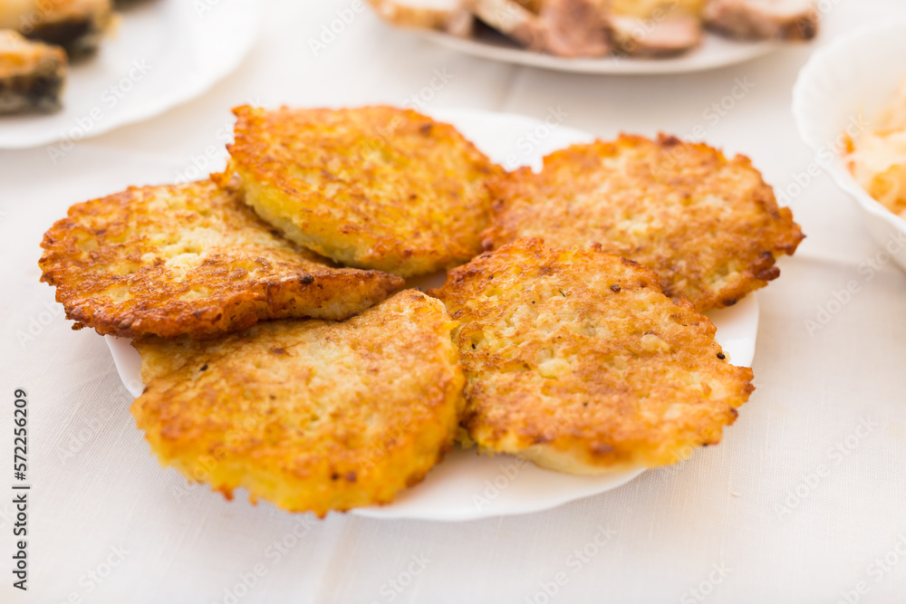 Fried grated potato pancakes with sour cream on white plate Fried grated potato pancakes with sour cream on white plate