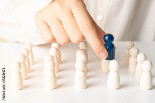 Hands take blue wooden figure out of crowd. Concept of rare disease, LGBTQ, virus epidemic, human resource, staff recruitment, talent, leadership and unique. photo