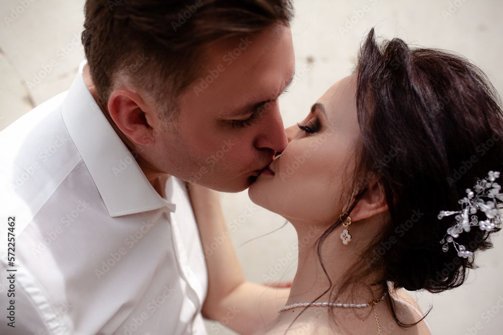 A couple in love, The bride and groom are dressed in a wedding suit and dress, hugging, kissing ech other and posing together A couple in love, The bride and groom are dressed in a wedding suit and dress, hugging, kissing ech other and posing together