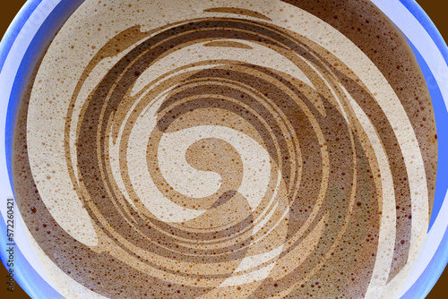 A creamy coffee closeup abstract with swirls and bubbles in a blue cup