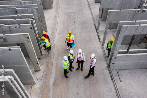Aerial top view of architect and engineer discussing building plan at construction building site in warehouse factory. Precast concrete manufacturing products on prefabricated house factory	 photo