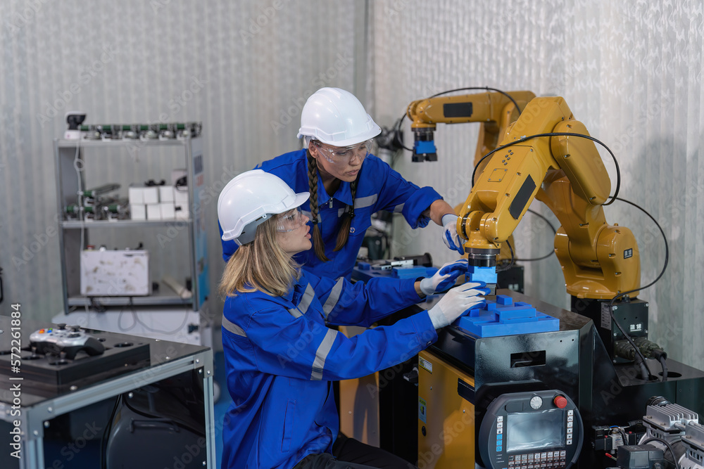 Female senior robotic engineer in modern factory teach new comer operate and maintenance robot arm Female senior robotic engineer in modern factory teach new comer operate and maintenance robot arm