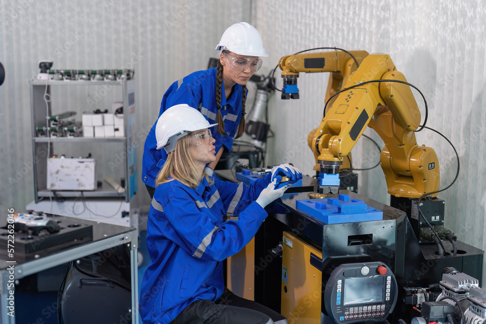 Female senior robotic engineer in modern factory teach new comer operate and maintenance robot arm Female senior robotic engineer in modern factory teach new comer operate and maintenance robot arm
