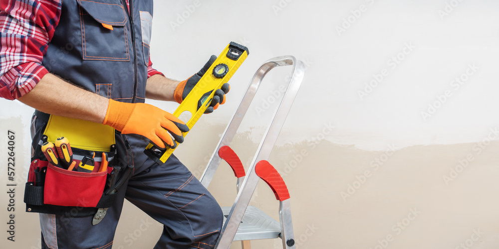 Builder handyman with construction tools near wall of room. Panoramic banner with copy space. Builder handyman with construction tools near wall of room. Panoramic banner with copy space.
