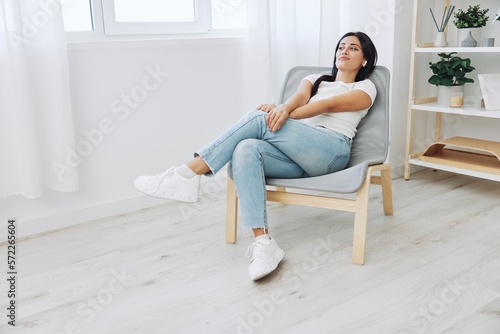 Woman sitting in a chair listening to music on wireless headphones at home