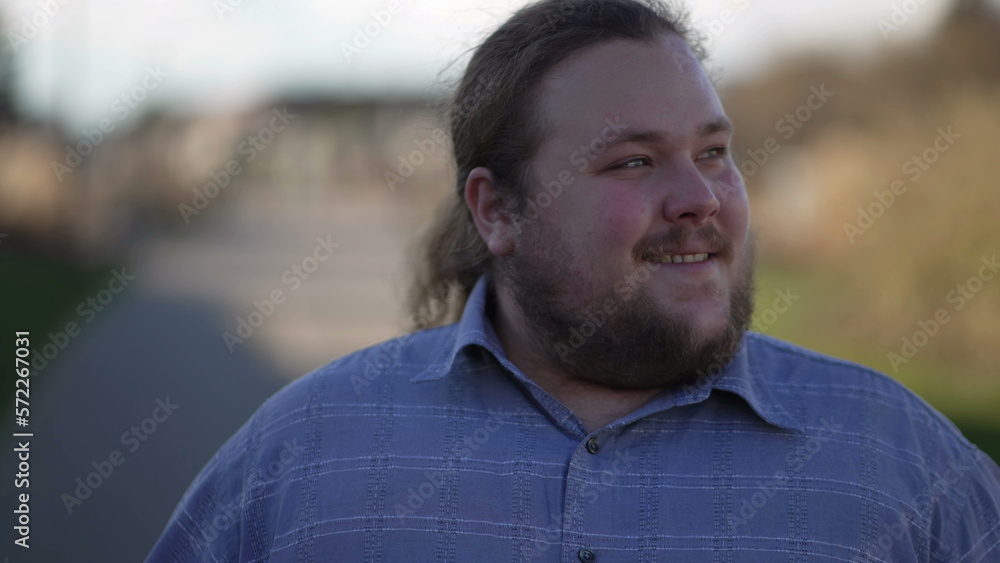 One happy young man walking forward outdoors with thoughful expression. Close up face of a smiling contemplative male person One happy young man walking forward outdoors with thoughful expression. Close up face of a smiling contemplative male person
