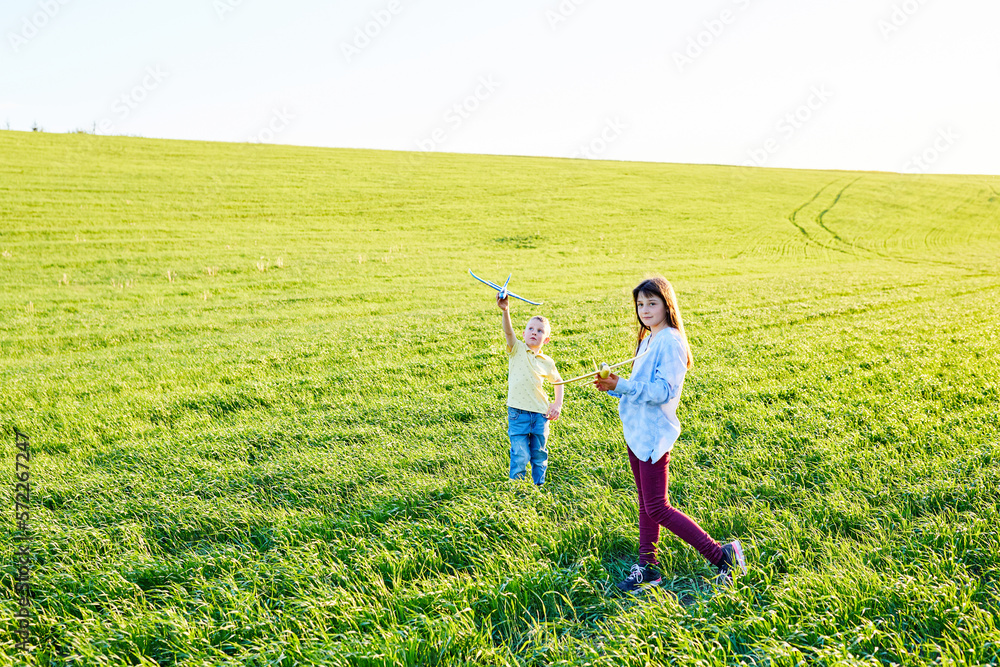 Cheerful and happy children play in the field and imagine themselves to be pilots on a sunny summer day. Kids dreams of flying and aviation.