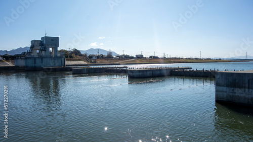 Принти на полотні 春の遠賀川水門と静かな水面の川の流れ、遠くに福智山を見る、The sluice gate of the Onga River and the quiet flow of the river, with a view of Mt