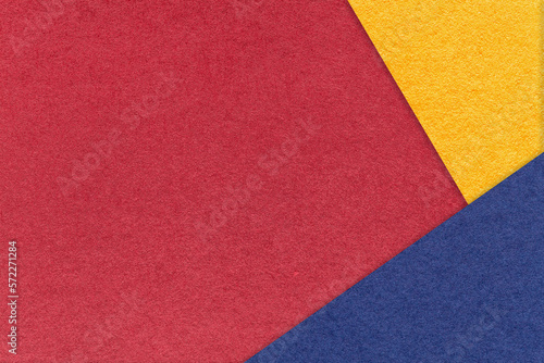 Texture of craft dark red paper background with yellow and blue border. Vintage abstract wine cardboard.
