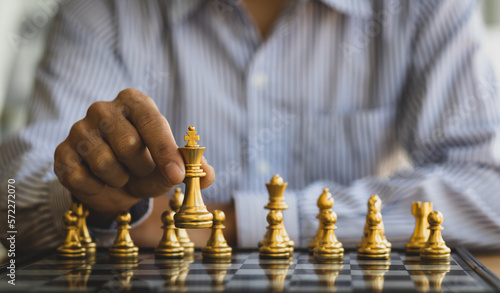 Businessman moving gold Chess King figure and Checkmate opponent during chessboard competition. Strategy, Success, management, business planning. Concept of business strategy and tactic.