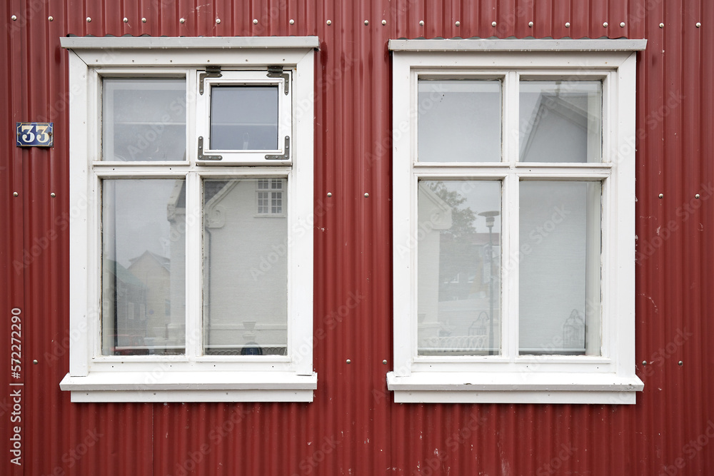 Red house facade with two white windows and red siding, with number 33, Reykjavik, Iceland Red house facade with two white windows and red siding, with number 33, Reykjavik, Iceland