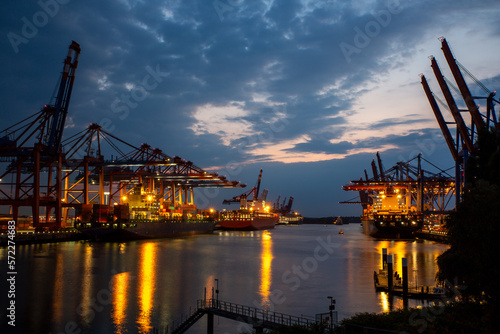 Hamburg Hafen Container Terminal mit Hafengiraffen und Frachtschiffen zur blauen Stunde Dämmerung