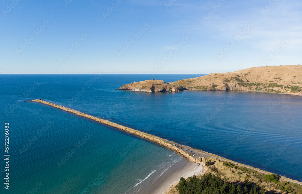An aerial view of the Aramoana Mole and Taiaroa Head in Dunedin, New Zealand, the entrance of Otago Harbour, and the habitat of penguins and royal albatross, as well as many other birds.