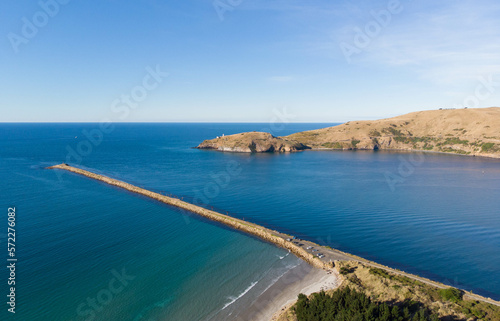 An aerial view of the Aramoana Mole and Taiaroa Head in Dunedin, New Zealand, the entrance of Otago Harbour, and the habitat of penguins and royal albatross, as well as many other birds.