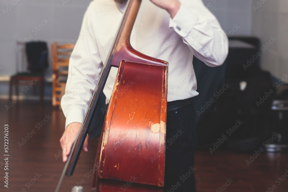 Contrabass cellist player in headphones during rehearsal, recording sound for new album song at studio, cello violoncellist musician with microphone and musical band orchestra, music production Contrabass cellist player in headphones during rehearsal, recording sound for new album song at studio, cello violoncellist musician with microphone and musical band orchestra, music production
