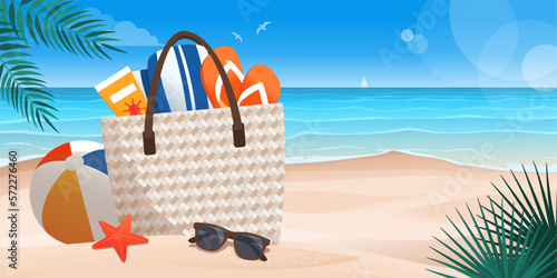 Beach bag with accessories on the sand and seascape