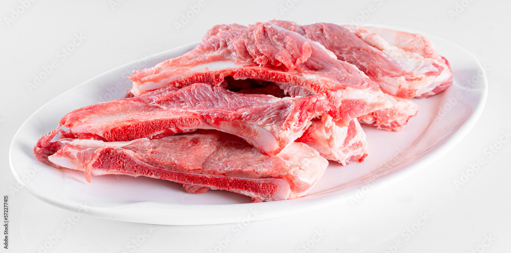 Fresh pork bone on white plate on white background Fresh pork bone on white plate on white background