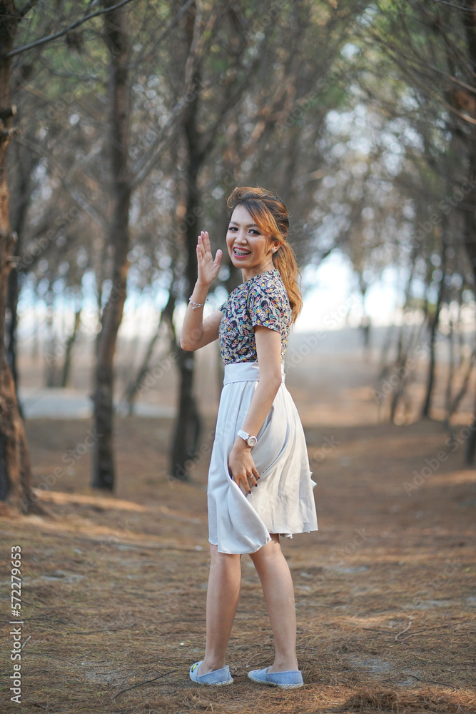 Woman Smiling and Waving Hand with Dry Branches Background Woman Smiling and Waving Hand with Dry Branches Background