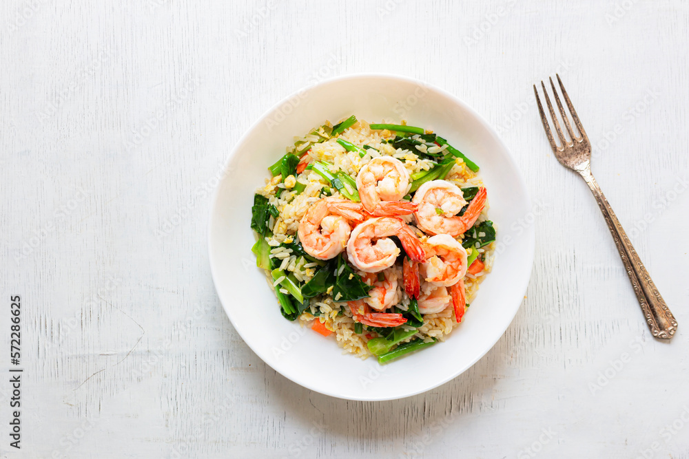 Fried rice with shrimp has vegetable in plate on white table. Fried rice with shrimp has vegetable in plate on white table.