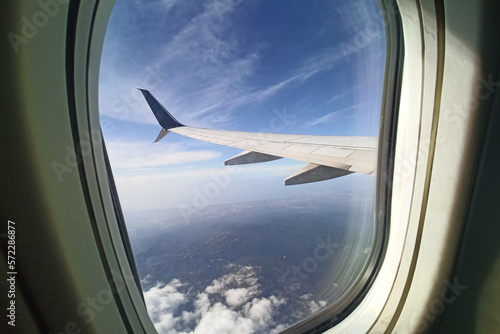 View through airplane window of commercial jet plane wing flying high in the sky. Air travelling concept