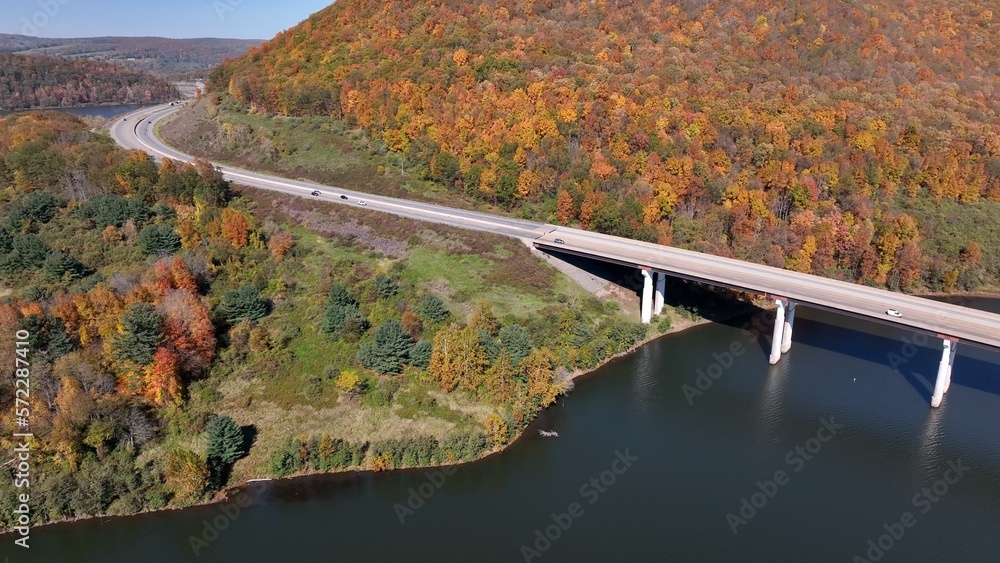 Cars and trucks traveling on highway crossing bridge over Tioga Reservoir in Autumn with Fall Colors Cars and trucks traveling on highway crossing bridge over Tioga Reservoir in Autumn with Fall Colors