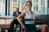 Cheerful woman in a wheelchair is in the office