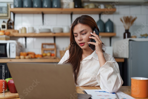 Asian Business woman working at kitchen room at home office and analyze financial report document. Accounting and Finance concept. © itchaznong