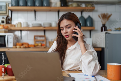 Asian Business woman working at kitchen room at home office and analyze financial report document. Accounting and Finance concept.