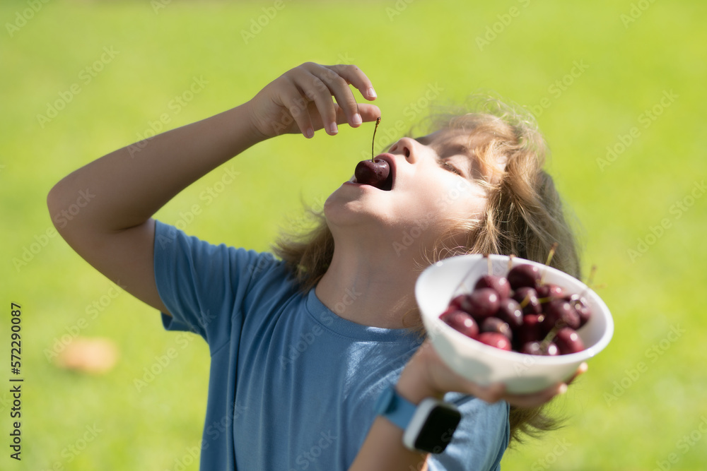 Cherry in kids mouth. Cherry fot kids. Happy kid eating ripe, sweet, juicy, fresh cherries. Child holding cherries. Concept of healthy summer food. Cherry in kids mouth. Cherry fot kids. Happy kid eating ripe, sweet, juicy, fresh cherries. Child holding cherries. Concept of healthy summer food.