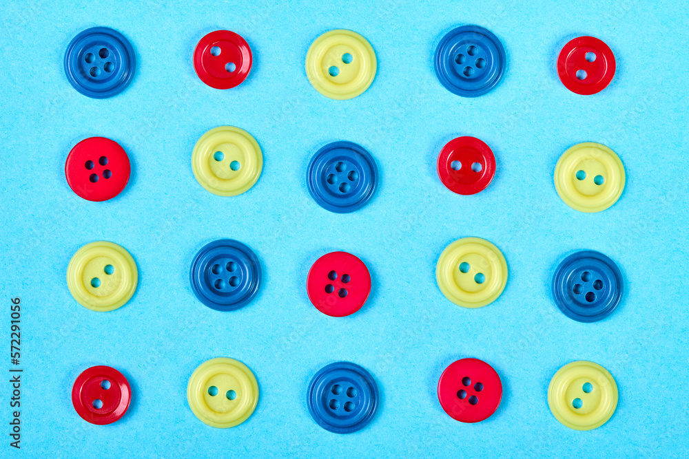 Fototapeta premium A set of multicolored buttons for clothess on a blue background
