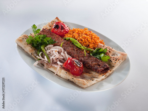 Adana kebab and garnish on pita bread photo