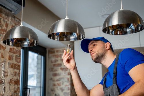 Quadro em tela Male electrician changes the light bulbs in the lamp