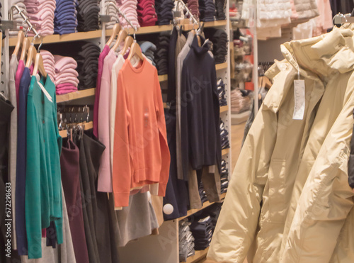 A colorful collection of women's autumn and winter clothing hangs on a hanger in the store