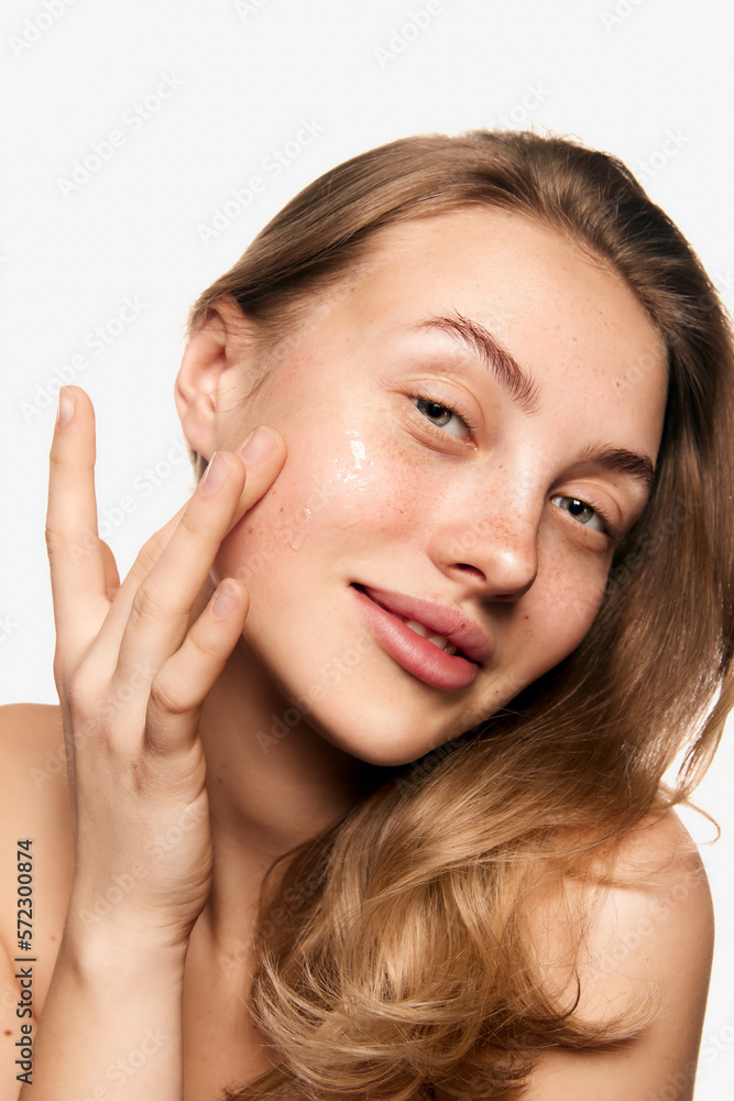 Closeup portrait of beautiful young girl with smooth clear skin and without makeup looking at camera with tenderness over white background. Concept of natural beauty Closeup portrait of beautiful young girl with smooth clear skin and without makeup looking at camera with tenderness over white background. Concept of natural beauty