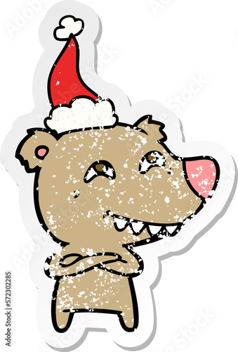 distressed sticker cartoon of a bear showing teeth wearing santa hat photo