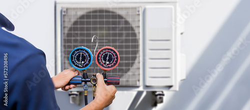 Photography Air repair mechanic using measuring equipment for filling industrial factory air conditioners