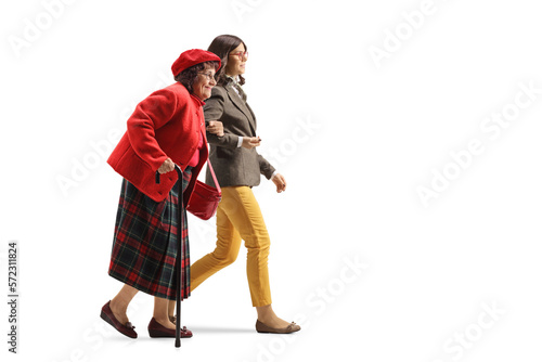 Young woman holding an older woman under arm and walking together