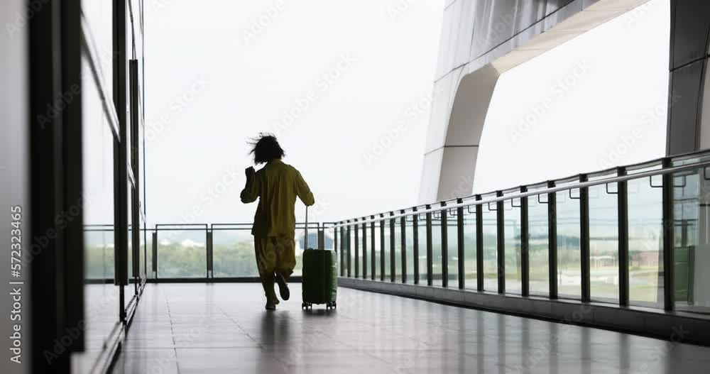 Back of woman traveler who rejoices at opening of borders after covid-19 epidemic. Adventurous woman can finally travel world calmly and freely. Woman dances while hopping through airport with luggage Back of woman traveler who rejoices at opening of borders after covid-19 epidemic. Adventurous woman can finally travel world calmly and freely. Woman dances while hopping through airport with luggage