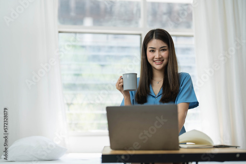 Happy, Relaxing Young beautiful Asian female watching movie or series on notebook in emotional smile happily while laying on the bed in her bedroom. Day off, Chill out and leisure concept.