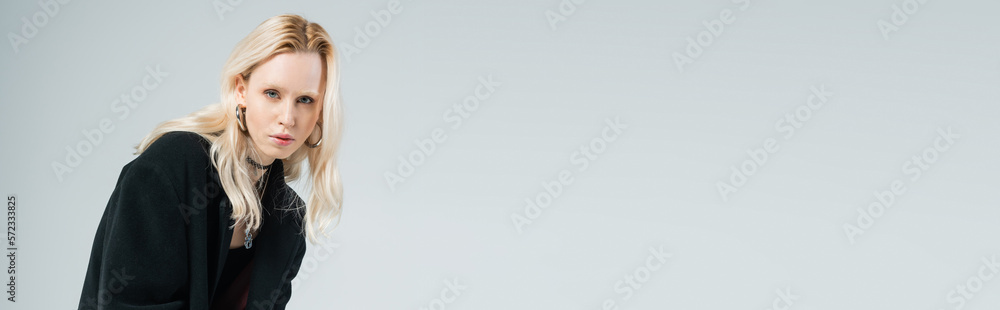 blonde woman in black outfit posing while looking at camera isolated on grey, banner. blonde woman in black outfit posing while looking at camera isolated on grey, banner.