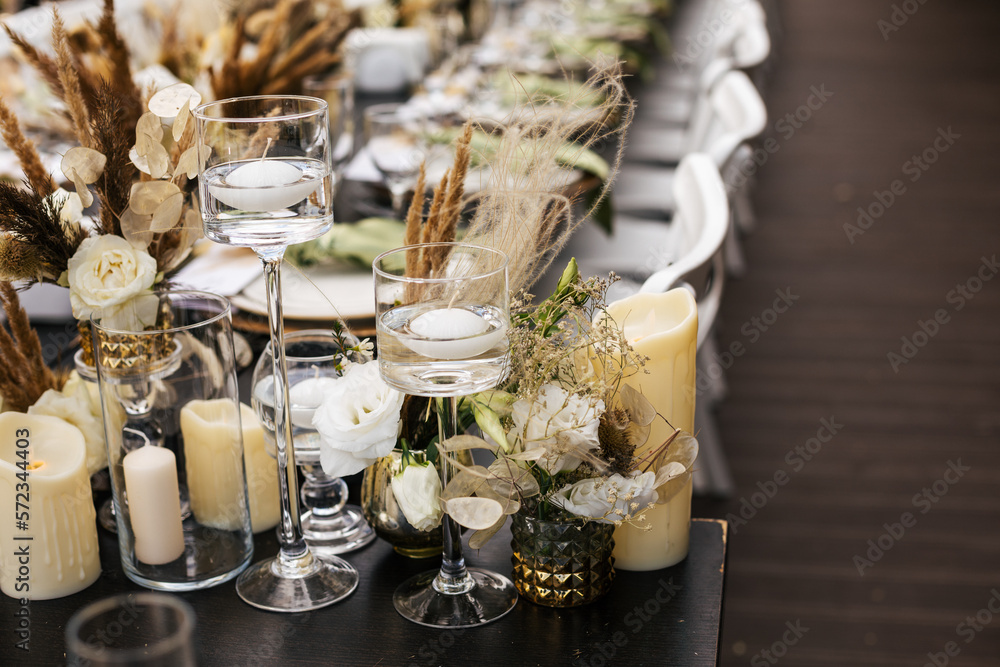 Wedding decorations.Close up of  decorative composition for wedding table with fresh and dried flowers, candles and and light bulbs. Celebration details, wedding outdoor
