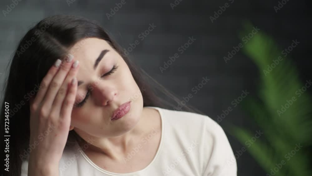 Tired young woman having headache. Video of attractive girl rubbing her forehead trying to figure out how to solve a problem. Difficult choice Tired young woman having headache. Video of attractive girl rubbing her forehead trying to figure out how to solve a problem. Difficult choice