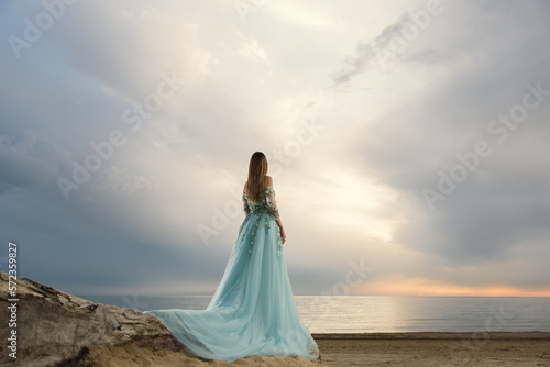  girl in a blue dress looking at the sea